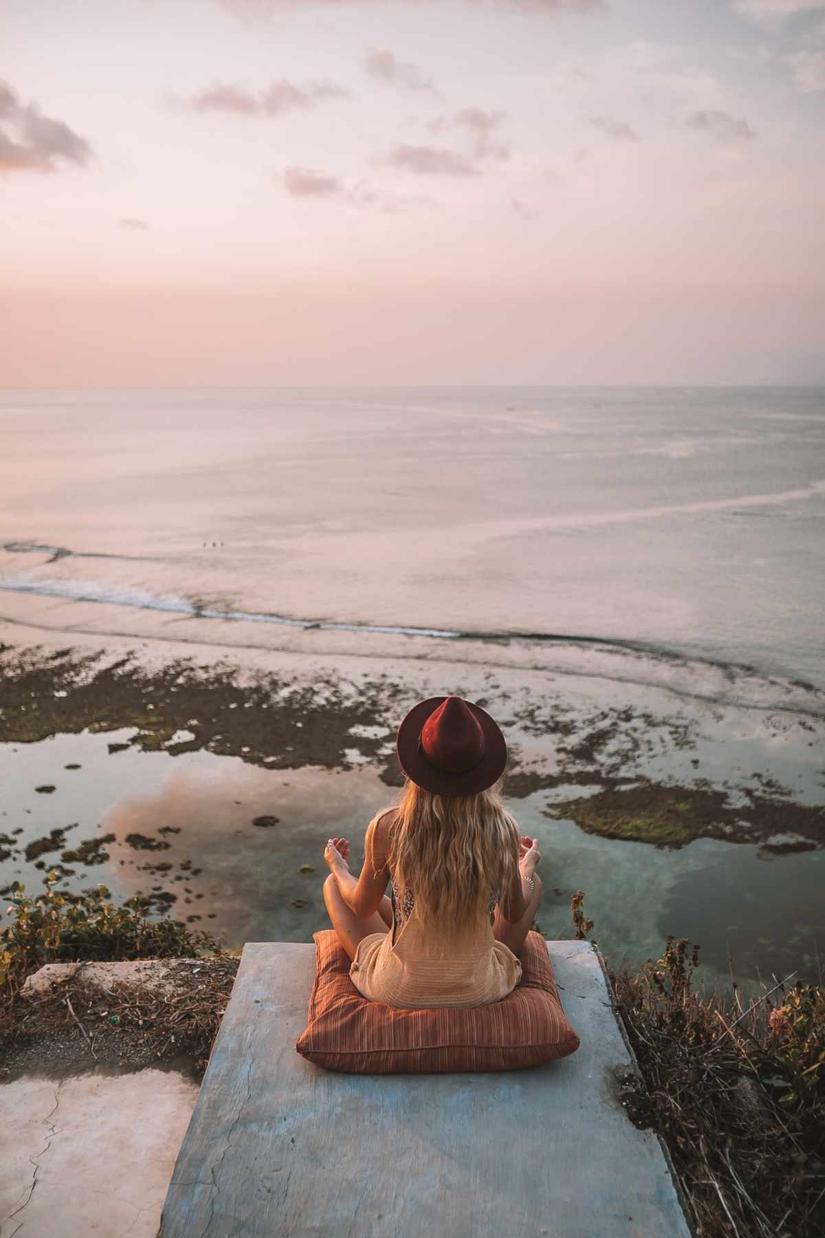 Rochelle meditating on a cliff at sunset