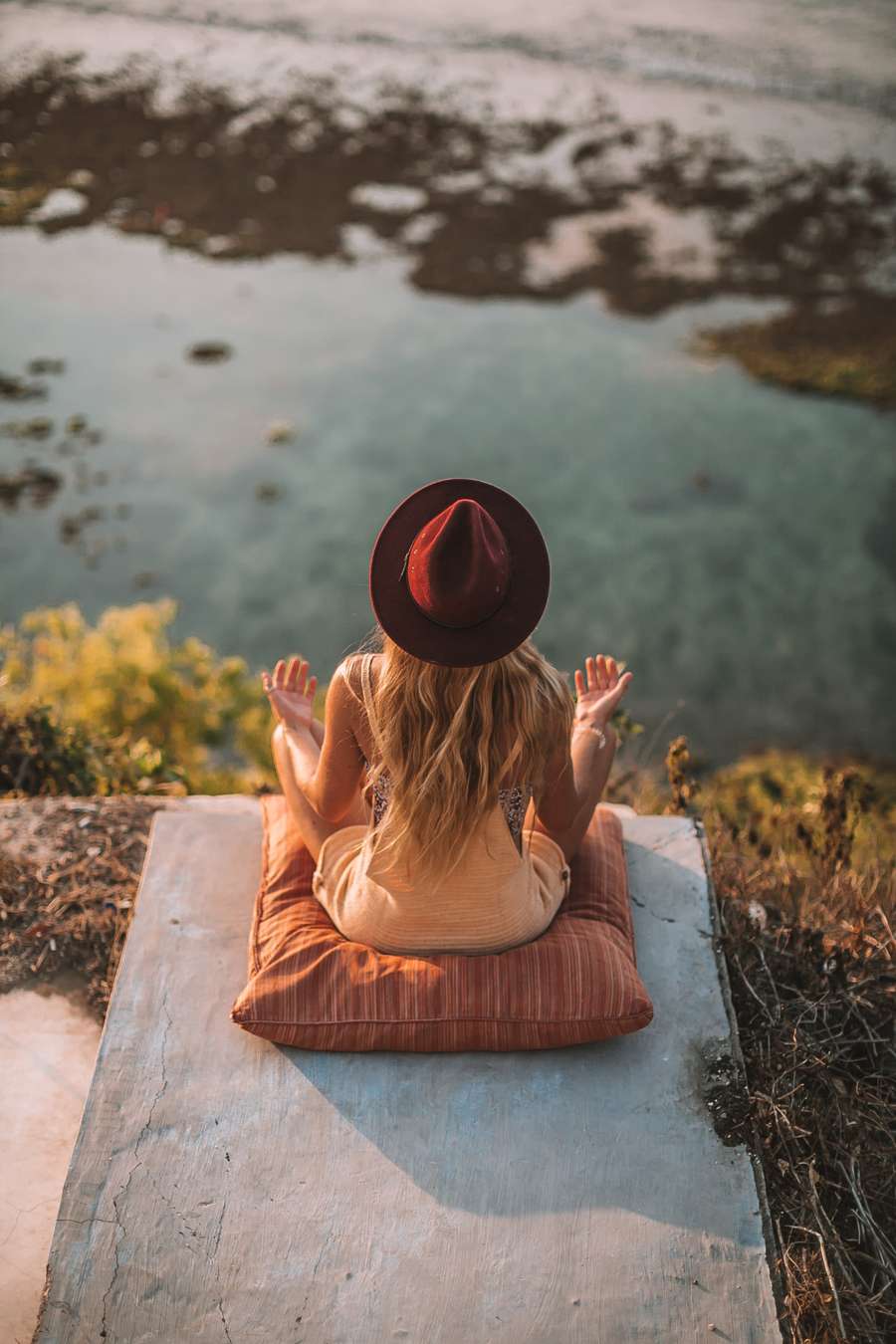 Woman meditating overlooking the ocean at sunset
