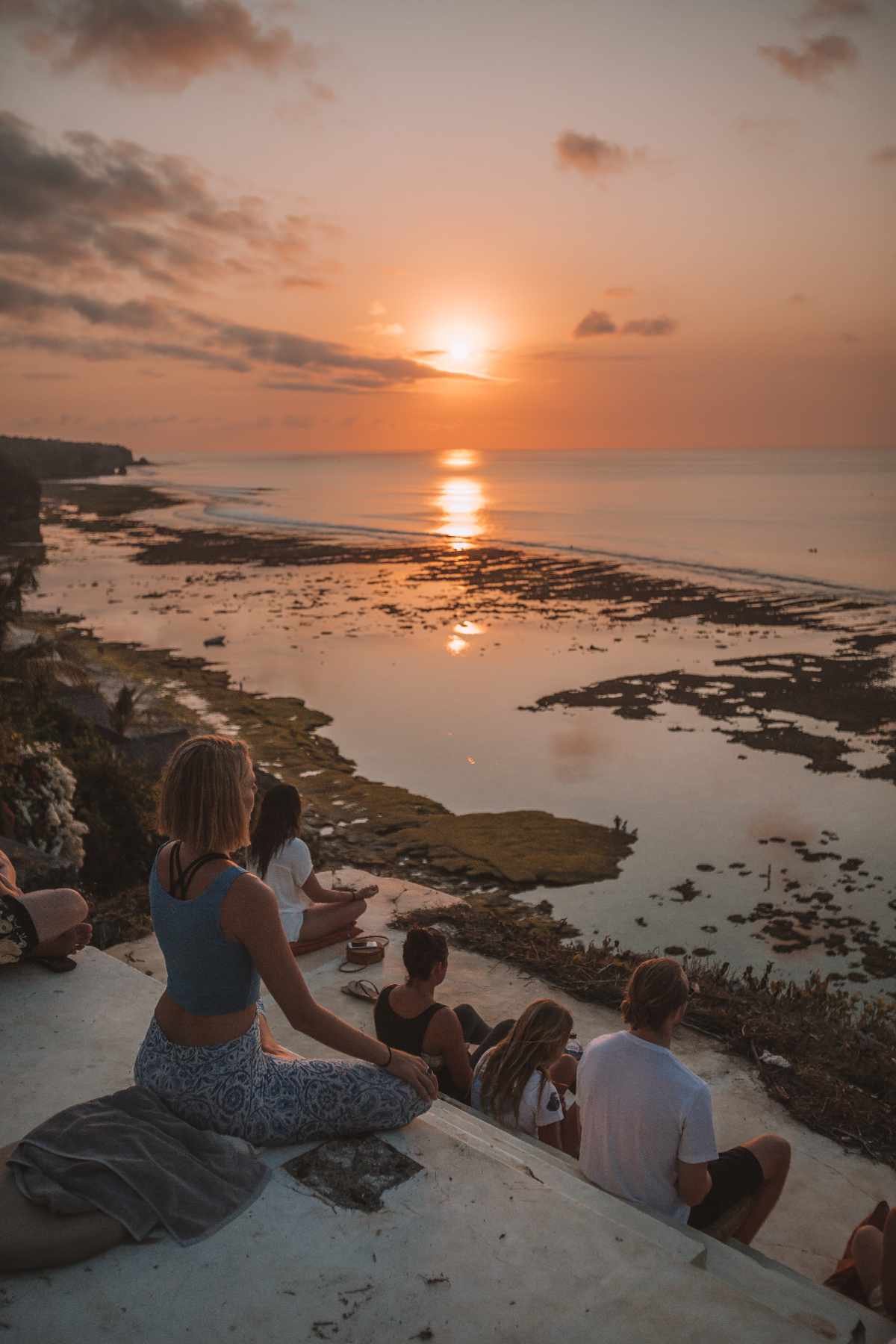 Group meditation at sunset on a Bali cliff